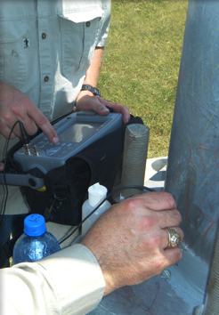 Technician performs ultrasonic testing of a weld connection on football stadium light pole.